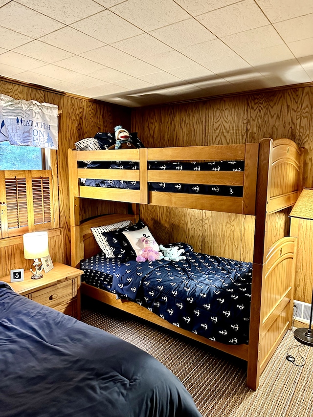 bedroom with carpet floors and wooden walls