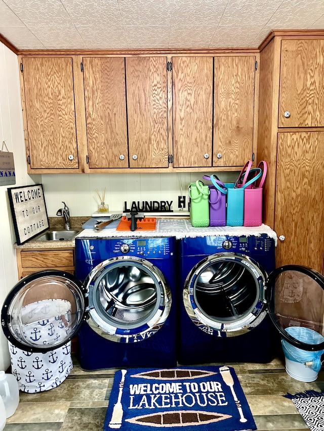 clothes washing area with sink, cabinets, a textured ceiling, and independent washer and dryer