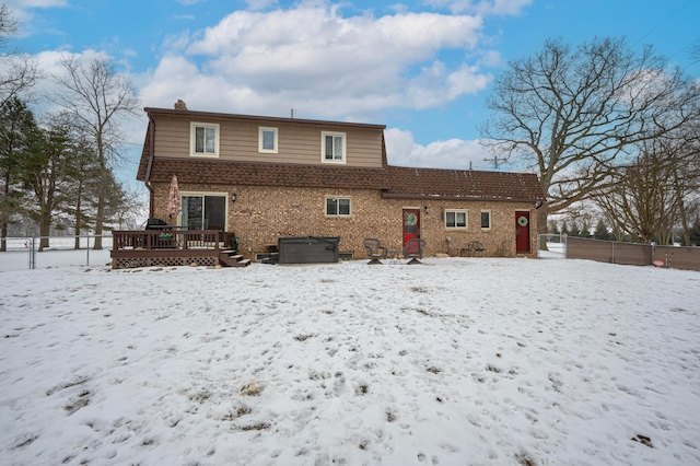 snow covered back of property featuring a deck and a jacuzzi