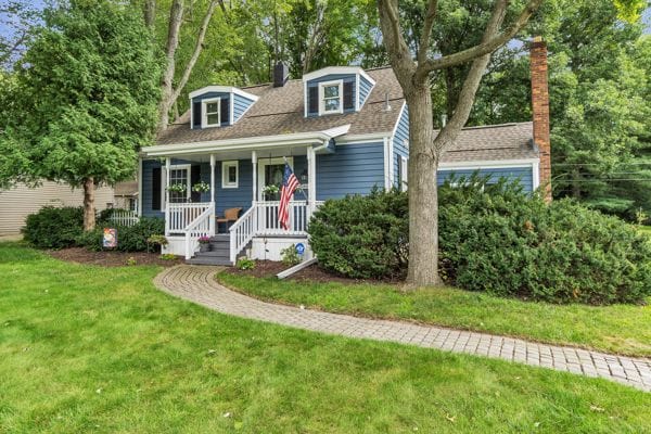 cape cod home featuring a front yard and a porch