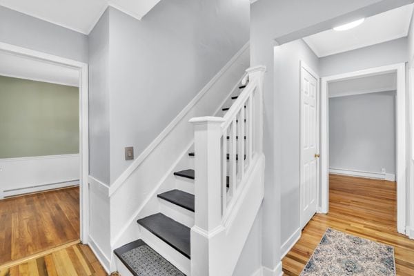 stairway with hardwood / wood-style floors and a baseboard radiator