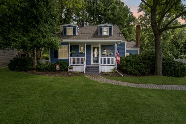 cape cod-style house with a porch and a yard