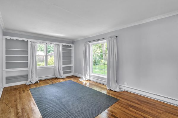 empty room with hardwood / wood-style floors, a healthy amount of sunlight, a baseboard radiator, and ornamental molding