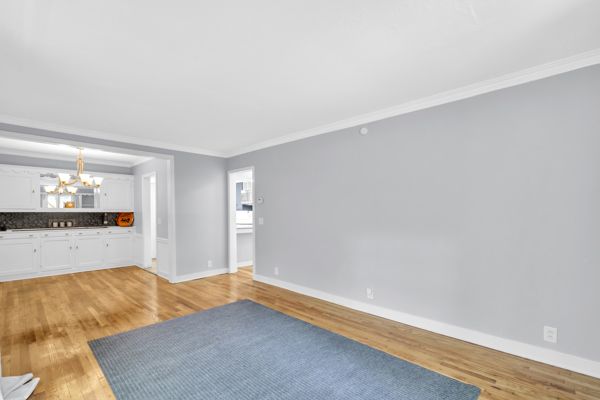 unfurnished living room with a chandelier, light wood-type flooring, and ornamental molding