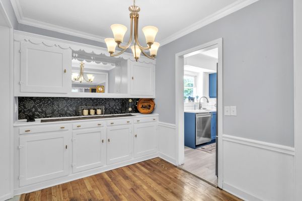 kitchen with dishwasher, hanging light fixtures, light hardwood / wood-style flooring, white cabinetry, and a chandelier