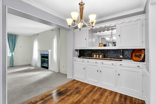 kitchen featuring white cabinets, crown molding, dark wood-type flooring, and tasteful backsplash