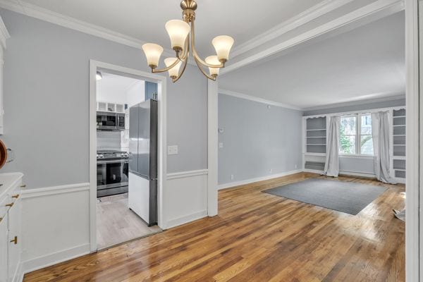 kitchen featuring white cabinetry, stainless steel appliances, light hardwood / wood-style flooring, a notable chandelier, and ornamental molding