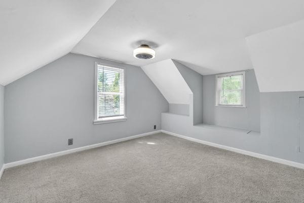 additional living space with plenty of natural light, light colored carpet, and lofted ceiling