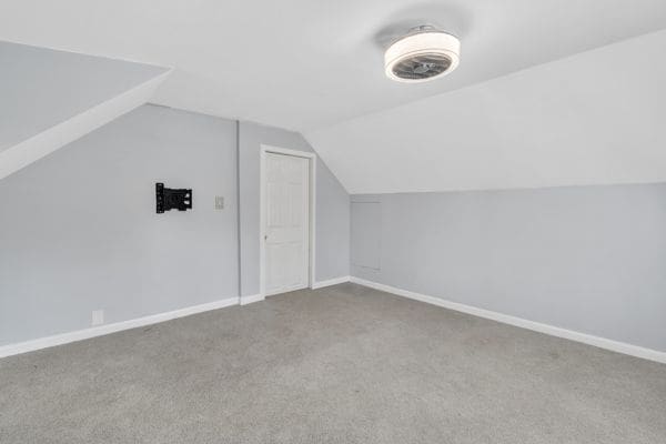 additional living space with carpet flooring and vaulted ceiling