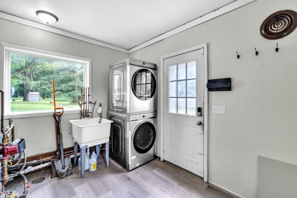 laundry room with ornamental molding, stacked washer / dryer, and light hardwood / wood-style flooring