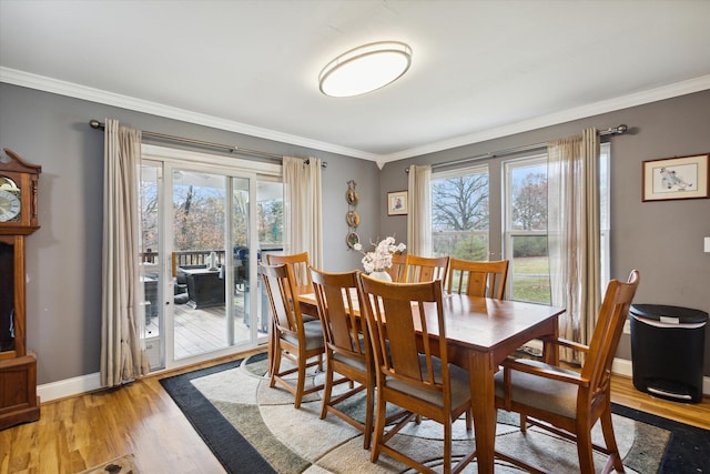 dining area with light wood-type flooring, plenty of natural light, and crown molding