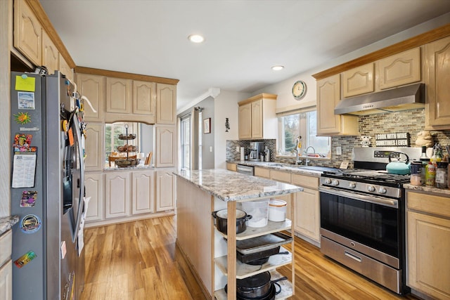 kitchen featuring a center island, decorative backsplash, light hardwood / wood-style floors, light stone counters, and stainless steel appliances