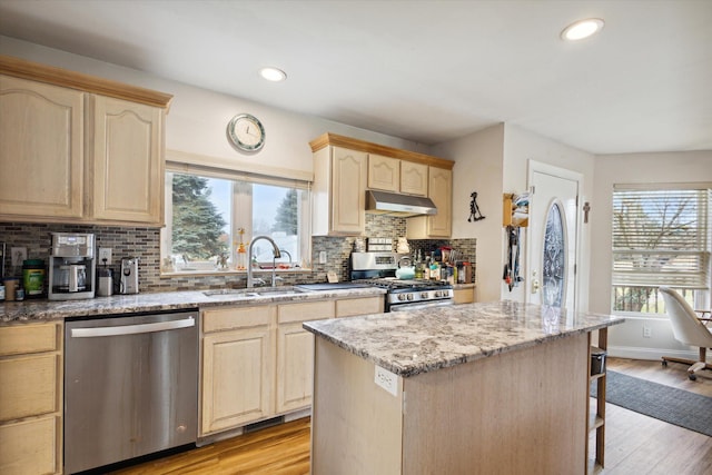 kitchen with light stone counters, sink, light hardwood / wood-style floors, and appliances with stainless steel finishes