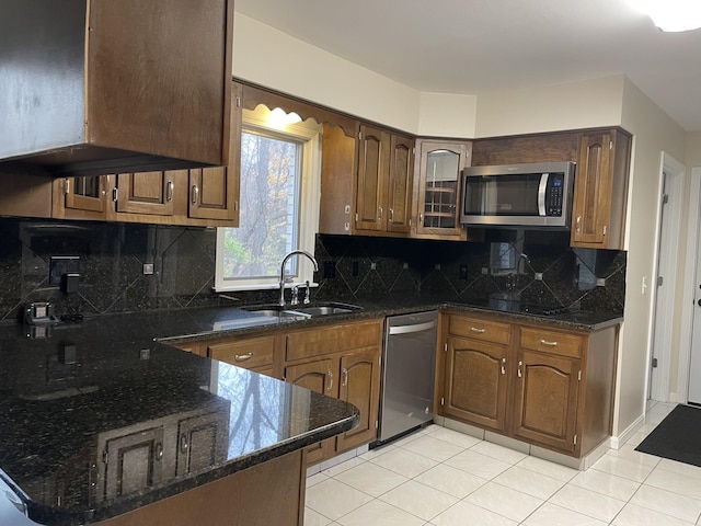 kitchen featuring sink, decorative backsplash, dark stone countertops, light tile patterned floors, and stainless steel appliances