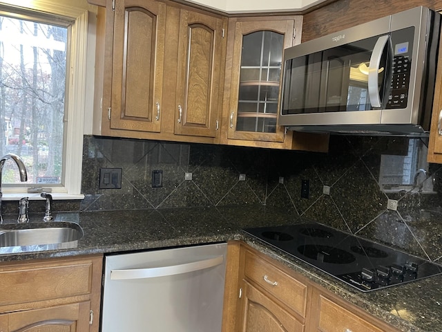 kitchen featuring backsplash, sink, stainless steel appliances, and dark stone counters