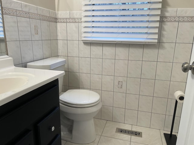 bathroom featuring tile patterned flooring, vanity, tile walls, and toilet