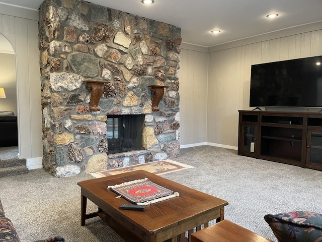 living room featuring wood walls, a fireplace, carpet floors, and ornamental molding