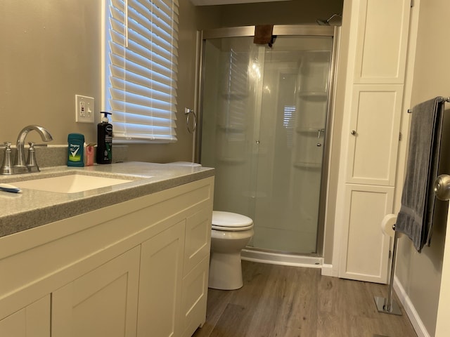 bathroom featuring hardwood / wood-style flooring, vanity, toilet, and a shower with door