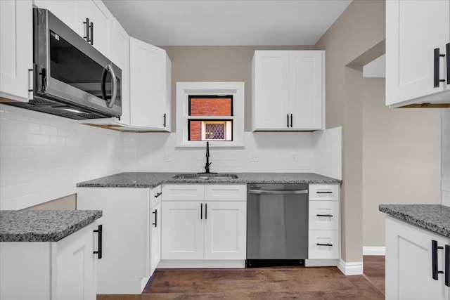 kitchen featuring white cabinetry, sink, stainless steel appliances, dark hardwood / wood-style flooring, and dark stone countertops