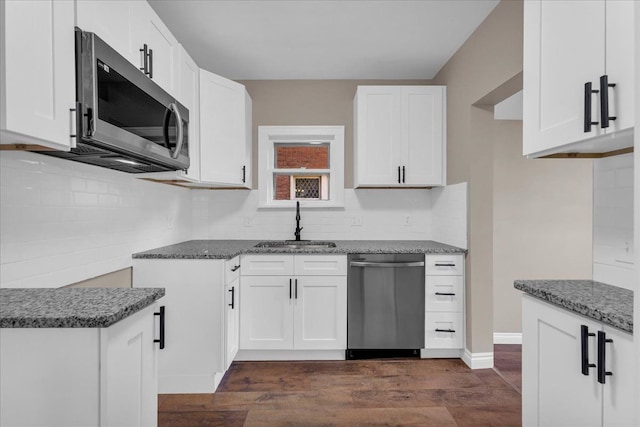 kitchen with appliances with stainless steel finishes, dark hardwood / wood-style flooring, sink, dark stone countertops, and white cabinets