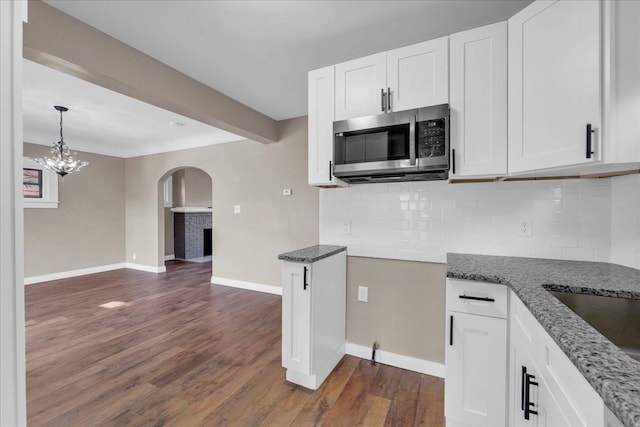 kitchen with white cabinetry, dark wood-type flooring, and tasteful backsplash