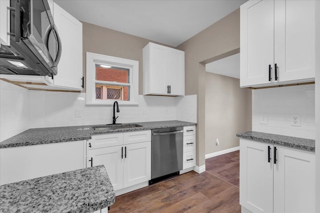 kitchen with sink, dark hardwood / wood-style floors, dark stone countertops, white cabinetry, and stainless steel appliances