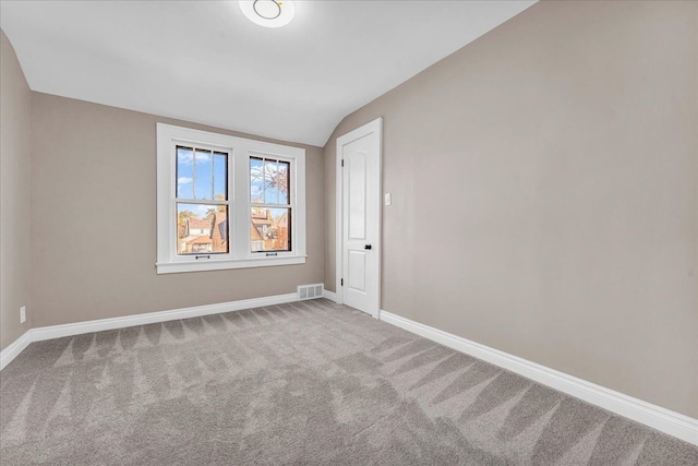 carpeted empty room with vaulted ceiling