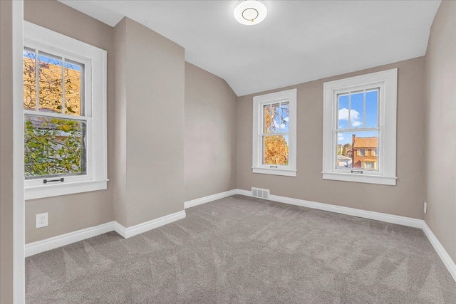 empty room with light colored carpet and lofted ceiling