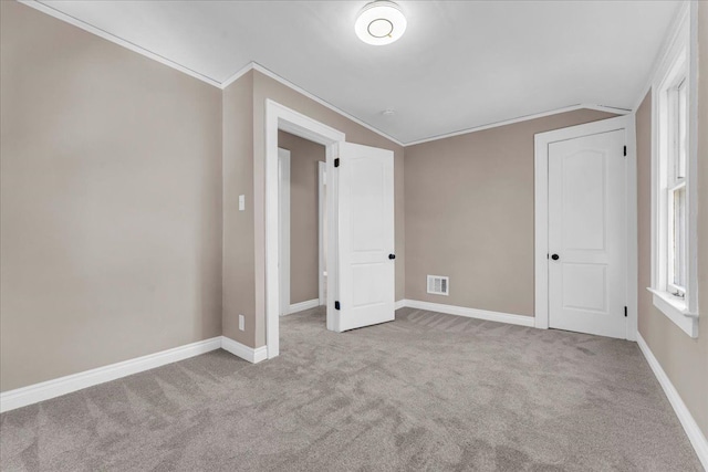 unfurnished bedroom featuring light carpet, crown molding, and lofted ceiling