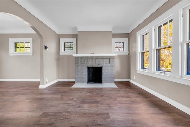 unfurnished living room with dark hardwood / wood-style flooring, crown molding, and a brick fireplace