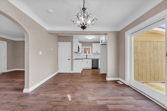 unfurnished dining area featuring wood-type flooring, sink, and an inviting chandelier