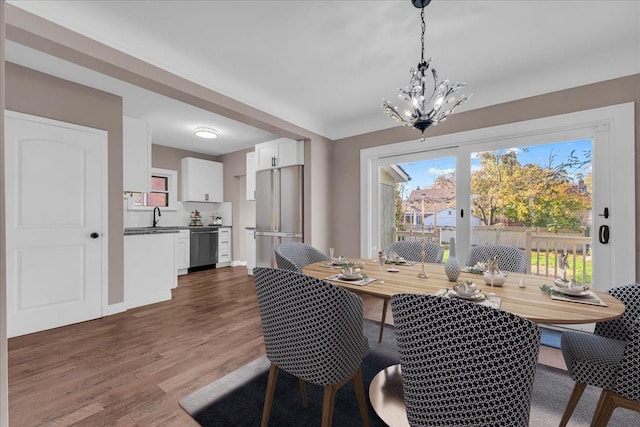 dining space with dark hardwood / wood-style flooring, a chandelier, and sink