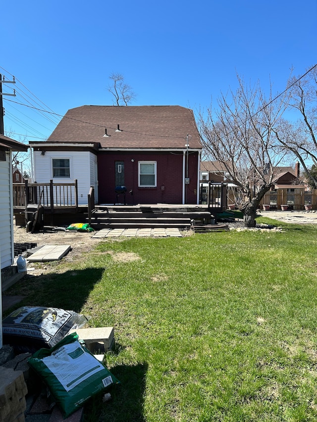 back of property featuring a wooden deck, a lawn, and roof with shingles
