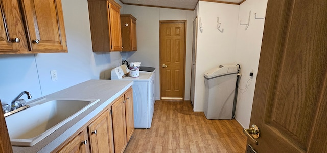 clothes washing area featuring sink, cabinets, light hardwood / wood-style flooring, crown molding, and washer / dryer