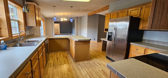 kitchen with sink, a chandelier, pendant lighting, a kitchen island, and light wood-type flooring