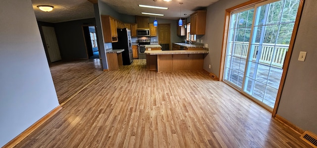 kitchen featuring pendant lighting, hardwood / wood-style floors, sink, kitchen peninsula, and stainless steel appliances