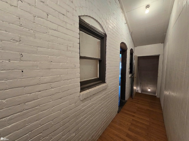 hall with dark hardwood / wood-style floors and brick wall