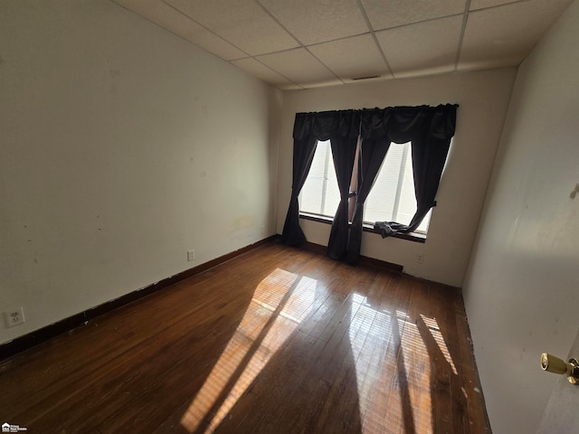 empty room with wood-type flooring and a paneled ceiling