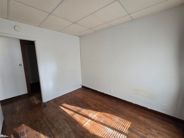 spare room featuring dark hardwood / wood-style floors and a drop ceiling