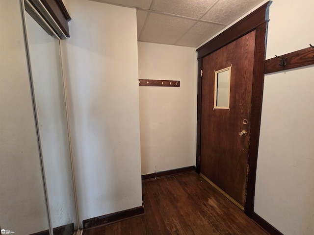 hall with a paneled ceiling and dark wood-type flooring