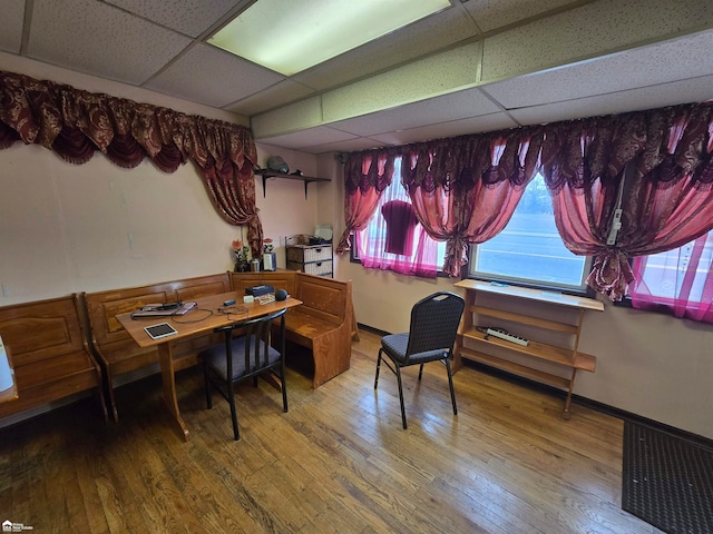 dining space featuring a drop ceiling and hardwood / wood-style flooring