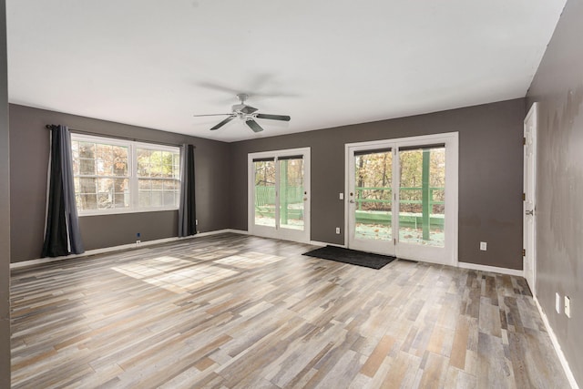 unfurnished room with light wood-style floors, ceiling fan, and baseboards