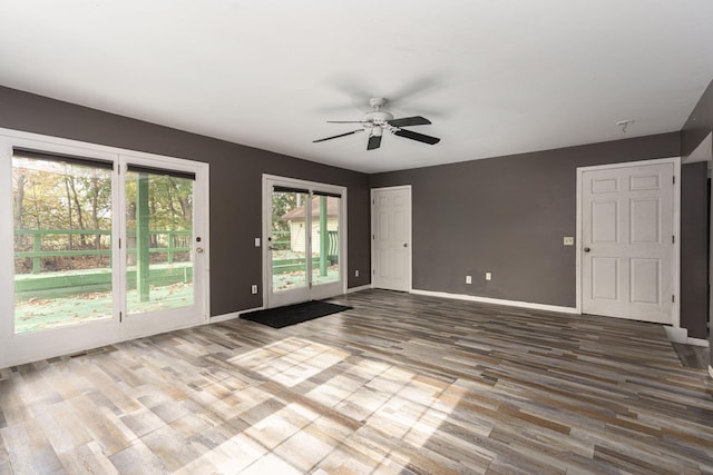 unfurnished room featuring a ceiling fan, baseboards, and wood finished floors