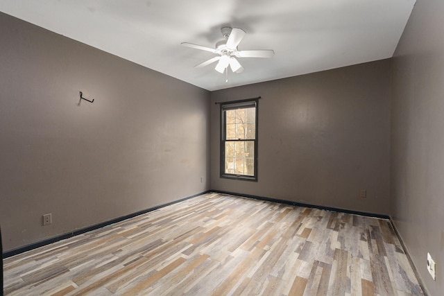 empty room with light wood finished floors, a ceiling fan, and baseboards