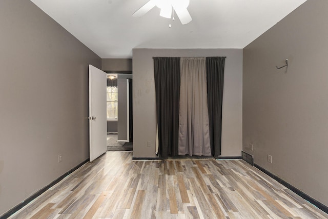 unfurnished room featuring visible vents, ceiling fan, light wood-style flooring, and baseboards