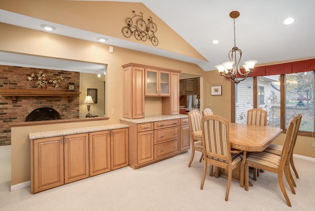 carpeted dining area with a fireplace, a chandelier, and vaulted ceiling