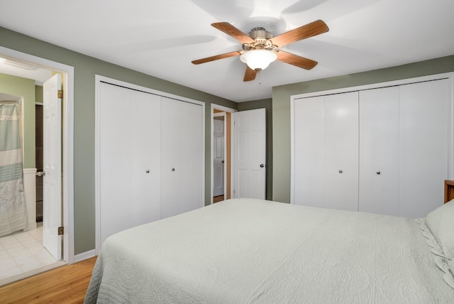 bedroom featuring ceiling fan, light hardwood / wood-style floors, connected bathroom, and two closets