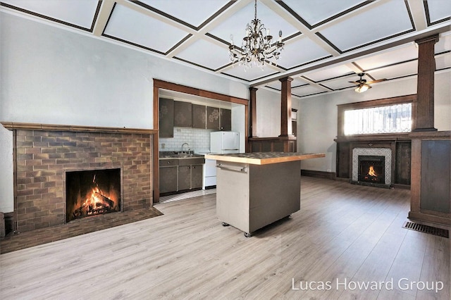 kitchen with ceiling fan, coffered ceiling, tasteful backsplash, light hardwood / wood-style flooring, and a breakfast bar