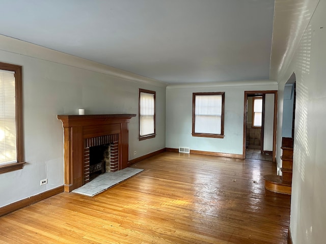 unfurnished living room with a fireplace, a wealth of natural light, and light hardwood / wood-style flooring