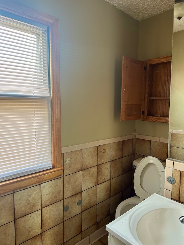 bathroom featuring sink, a textured ceiling, and tile walls